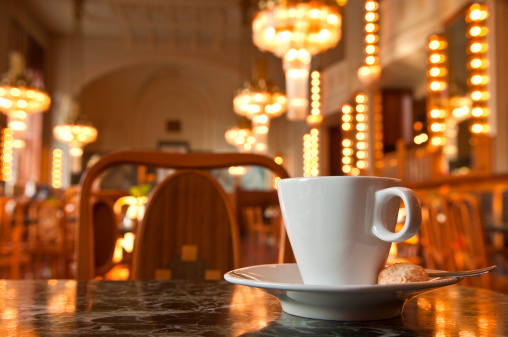 Refreshing coffee with a backdrop of Art Deco lighting in Prague cafe, Czech Republic. Shallow depth of field for copy space.