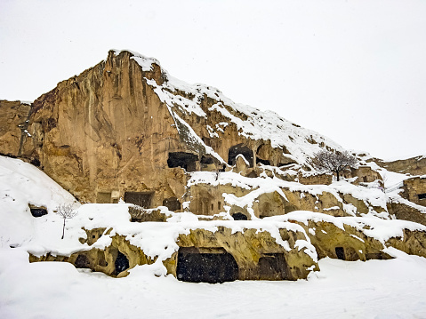 Beautiful view in Ürgüp, Cappadocia with astonishing rock formations. Historical area covered with snow. Rock hoodoo winter landscape background, copy space.