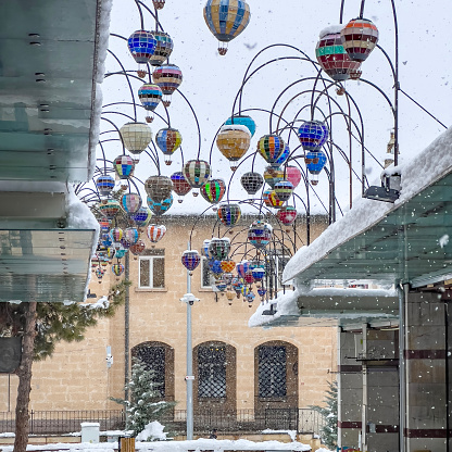 Groups of hot air balloon during day hanging over the grand bazaar in Urgup, Cappadocia. Globes with a mosaic design made from pieces of colored glass.