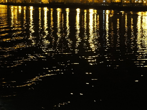 Lines of reflection of yellow lights at night on harbour water, San Fransisco