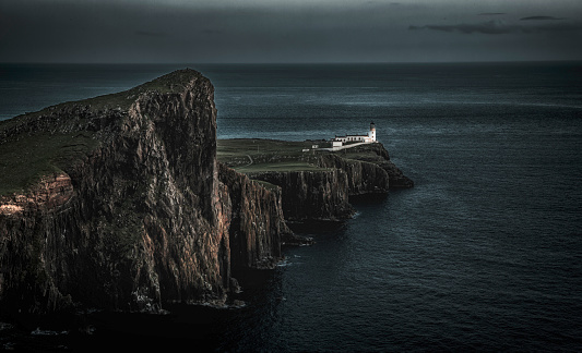 The view of the Neist Point Lighthouse and the Neist cliff on the west coast of the Isle of Skye under the dark sky