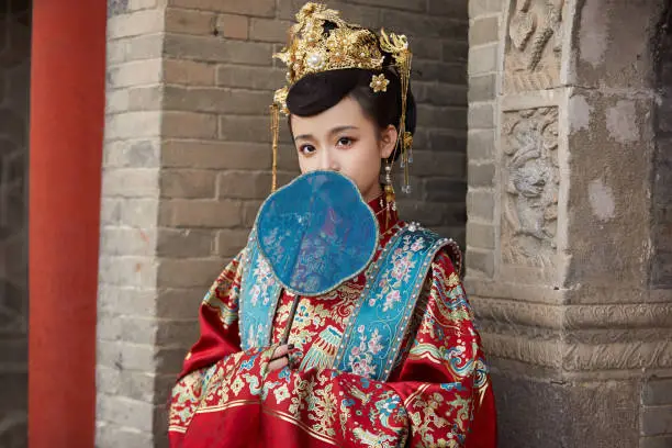A young Asian girl dressed in ancient attire, exploring and enjoying her surroundings
