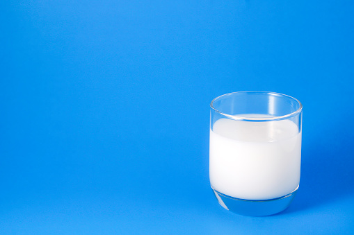 The image of milk in a glass has a composition. A glass of milk is placed on the right hand side.