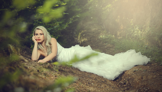 sensual bride lying down in forest.