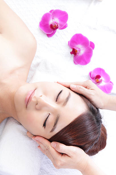 美しい若い女性の受信顔のマッサージをお楽しみください。 - beauty spa spa treatment health spa orchid ストックフォトと画像