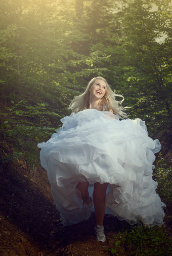 happy and excited bride jumping in forest.