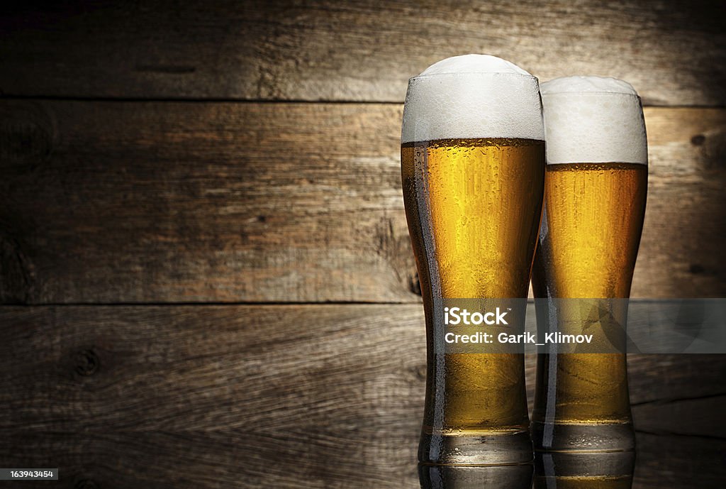 Due bicchiere di birra su un tavolo in legno di sfondo - Foto stock royalty-free di Alchol