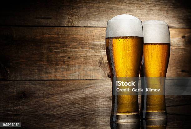 Due Bicchiere Di Birra Su Un Tavolo In Legno Di Sfondo - Fotografie stock e altre immagini di Alchol