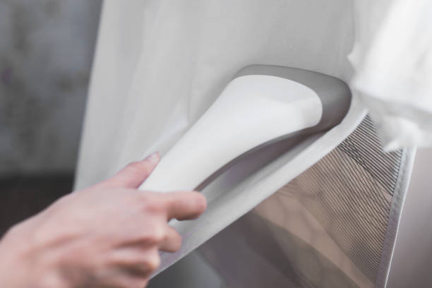 istock Close-up on a steamer in hand steaming white clothes on a hanger 1639456904