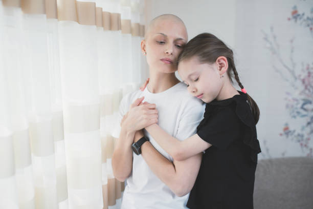 ragazza preadolescente che abbraccia la madre malata senza peli con l'oncologia. ritratto di paziente malata dopo la chemioterapia che abbraccia la piccola figlia che la visita in reparto - cancer chemotherapy drug baby family foto e immagini stock