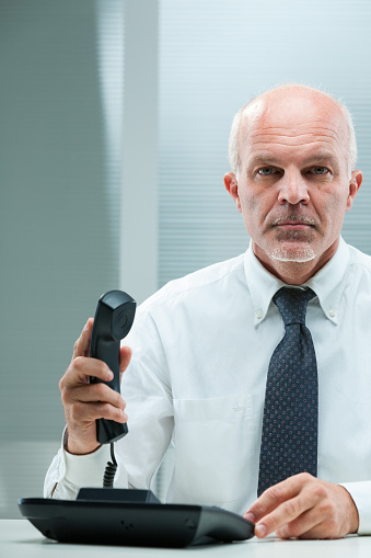 Immediate challenges demand direct intervention. A businessman in formal wear, seated by his computer, lifts the phone. The urgency and seriousness of business guide his dialogue and negotiation