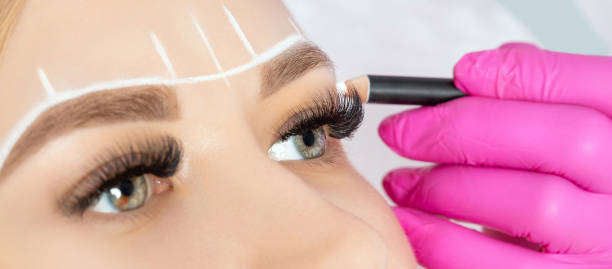 istock Woman Having Permanent Make-up Tattoo on her Eyebrows.Permanent make-up for eyebrows in beauty salon. Closeup beautician doing tattooing eyebrow. Professional makeup and cosmetology skin care. 1639564726
