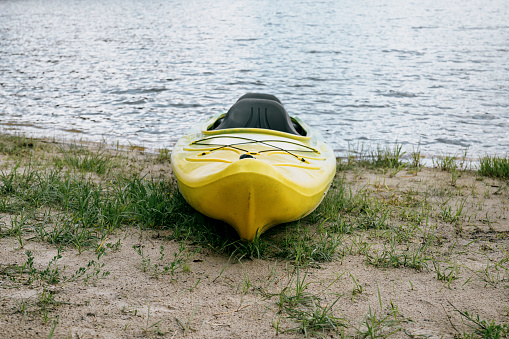 A single empty kayak on the shore of a yellow lake. Front view