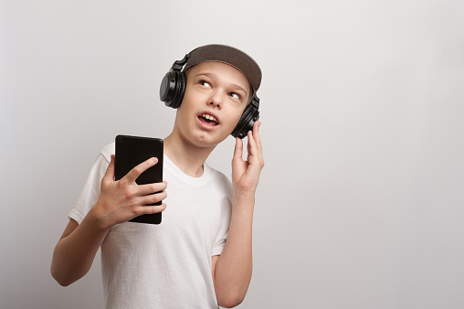 A boy with tablet and headphones poses in a casual style