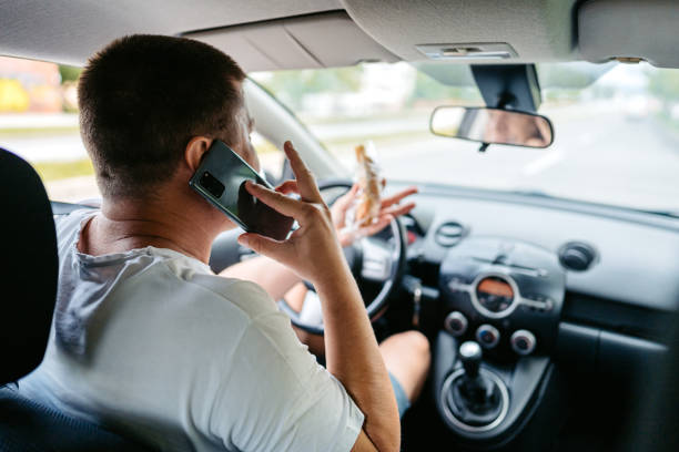 istock Young Man Eating And Talking On The Phone While Driving A Car 1639628942