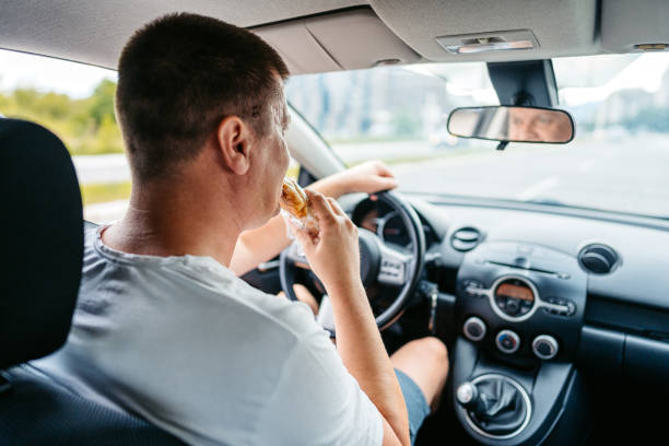 istock Young Man Eating A Sandwich While Driving A Car 1639631551