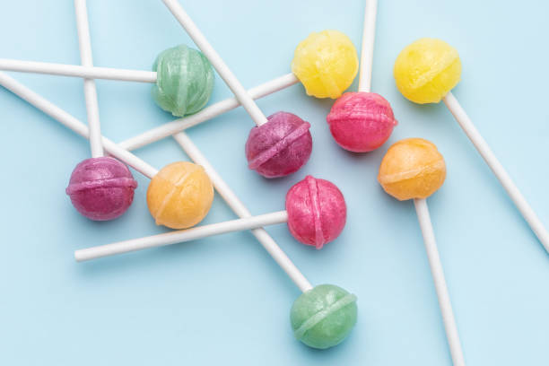 Colorful sweet lollipops and candies over blue background.  Flat lay, top view