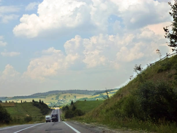 istock Trucks drive along the asphalt road in the future. Blue sky above them 1639675238
