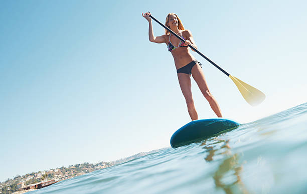 Perfect day for a paddle A beautiful woman out on the sea standing on her paddle board paddleboard surfing oar water sport stock pictures, royalty-free photos & images