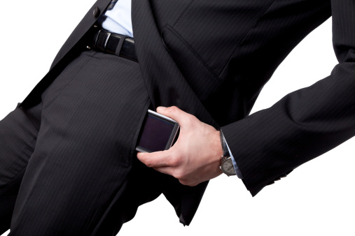 Well dressed business man, putting smartphone in pocket