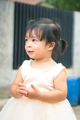 A cute little girl is white dress during playing air soap bubble with happiness action in the wedding event. Girl portrait photo, face focus.