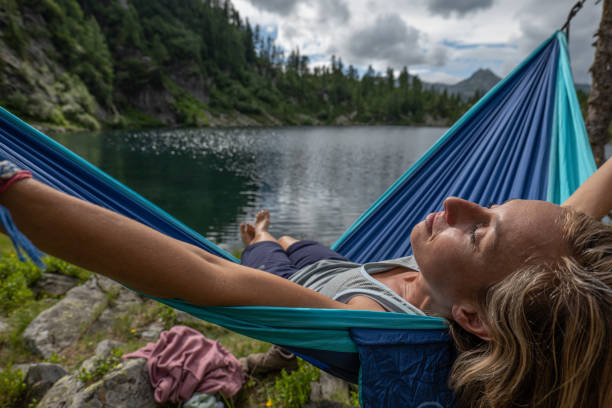 istock Woman camping by the lake en joys her hammock 1639736366