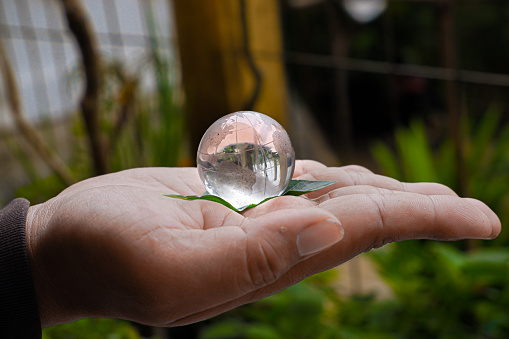 a miniature globe made of crystal sits on top of the palm.