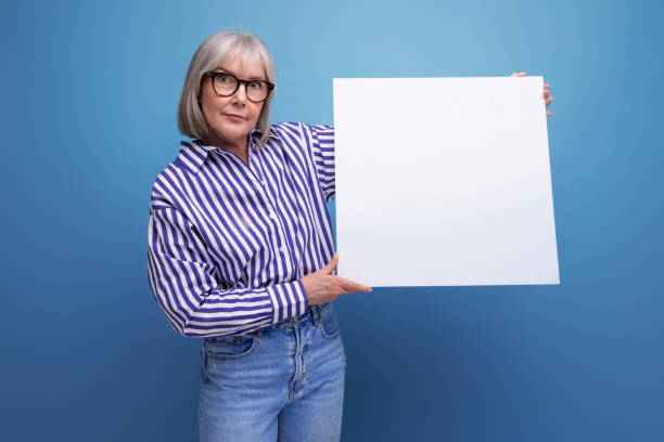 istock middle-aged business lady showing blank billboard with mockup on bright studio background 1639803803