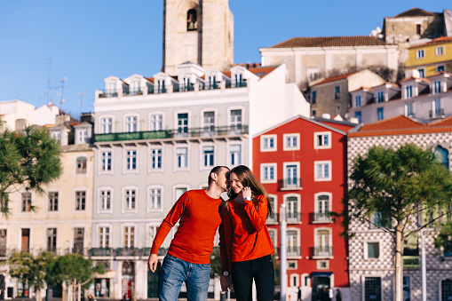 couple in love in red sweaters. guy kisses girl on the background of beautiful buildings.
