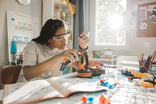 Teenage girl working on electronic project at her room at home.