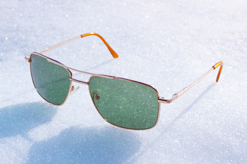 Special green lens sunglasses on white winter snow and sunlight