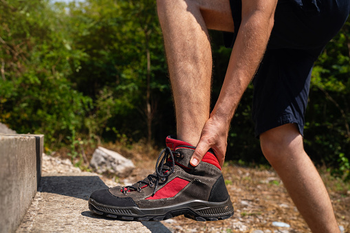 During his hike in nature, a mid-adult Caucasian man experiencing pain in his ankle