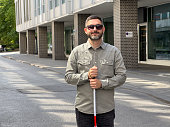 Portrait of a Caucasian man with visual impairments, holding a cane