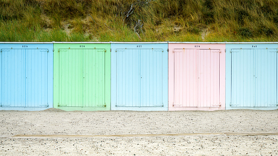 Colorful beach cabins at North Sea beach of Domburg, Zeeland, the Netherlands in front of overgrown sand dunes