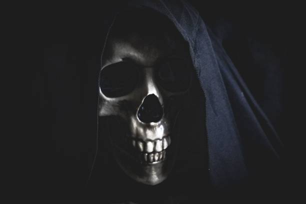 istock Black hooded human skull illuminated in the dark. 1639887643