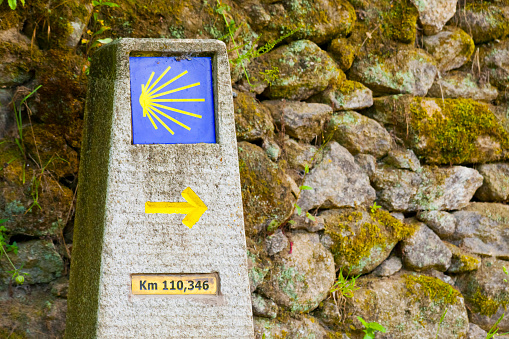 Camino de Santiago pilgrimage route, yellow arrow and scallop symbols.  Belesar village , Ribeira Sacra winemaking and touristic area, Lugo province, Galicia, Spain. Copy space on the right.