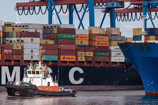 Hamburg, Germany - April 10, 2019: ‘Bugsier 2’ towing container ship to the HHLA Container Terminal Altenwerder (CTA).