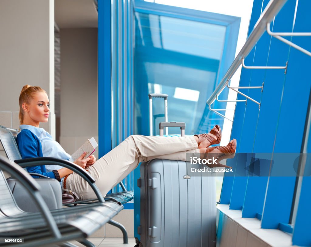 Waiting for the flight Beautiful young adult woman waiting for her flight at the airport lounge, looking out the window. Airport Stock Photo