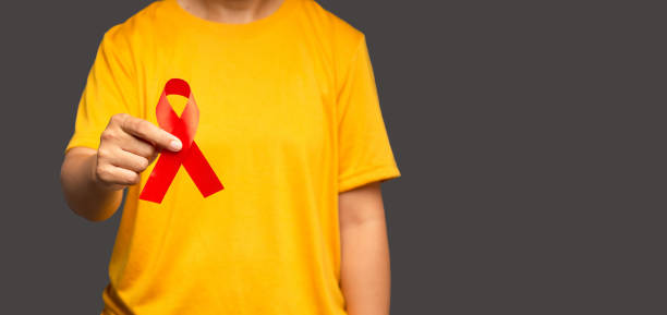 istock Hand holding a red ribbon for December World AIDS Day while standing on a gray background 1639962237