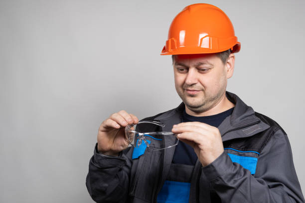 istock A construction worker in a helmet and overalls put on goggles protective glasses on a white background. 1639962242