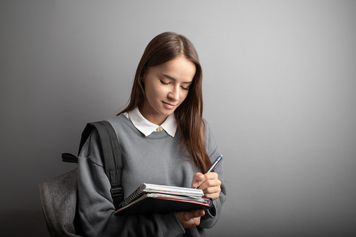 Student girl with a backpack, carrying a notebook and textbook, Teenager studying,