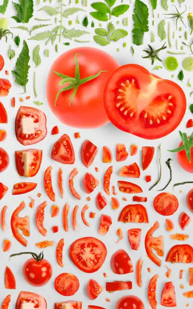 Abstract background made of Red Tomato vegetable pieces, slices and leaves isolated on gray background.