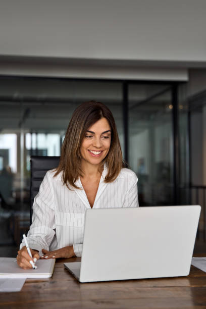 istock Middle-age Hispanic woman using laptop computer for business studying, watch online virtual webinar training meeting,video call. Focused mature 40s years Latin businesswoman work in office, vertical 1640022007