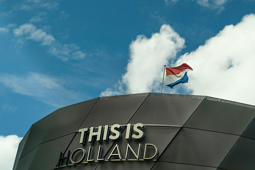 The flag of the United Kingdom of Great Britain and Northern Ireland, known as Union Flag or Union Jack, hanging down loosely at full-mast on a white pole against blue sky.