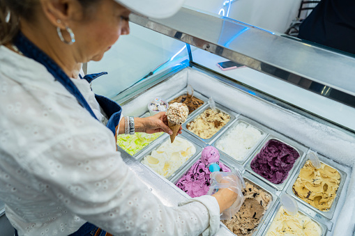 average age 40-year-old Latina woman dressed formally entrepreneurial owner of a small ice cream business serves her customers by serving them a delicious ice cream