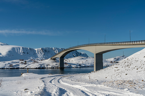 Long bridge connecting islands at Torsfjorden fjord near village Fredvang on island of Moskenesøya in the Lofoten archipelago in Nordland county in winter. Low angle view.