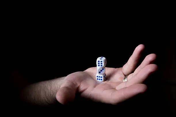 dice on a palm, isolated black background, stand the pyramid