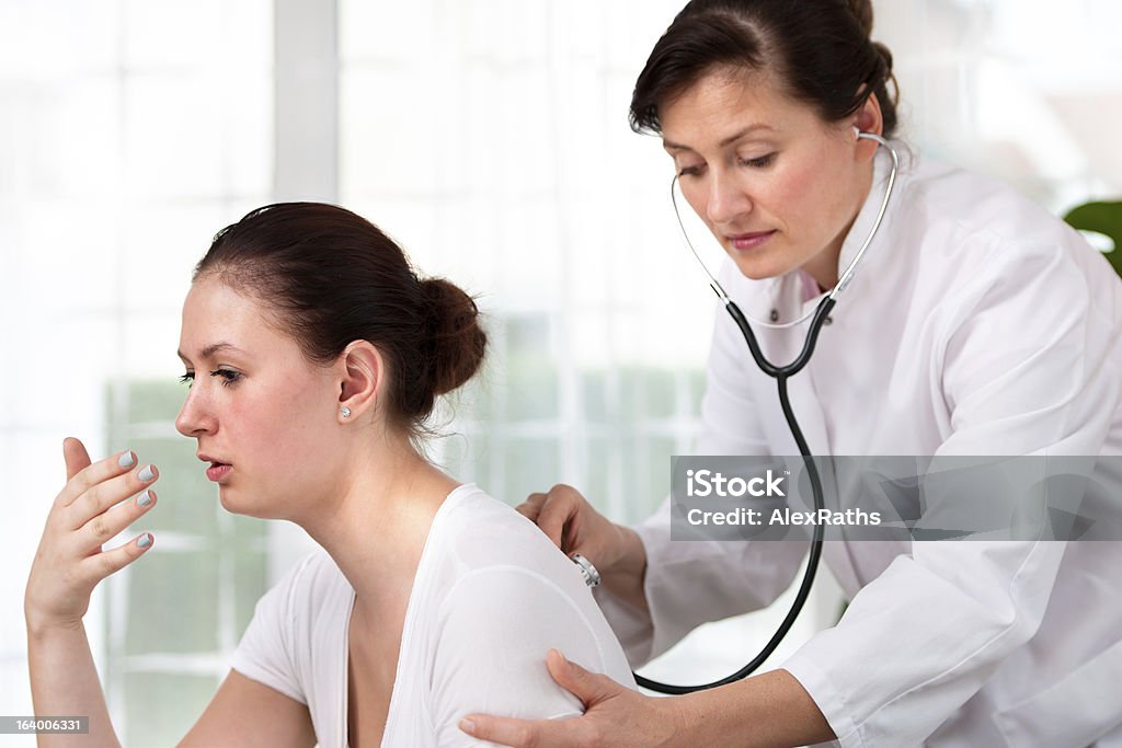 Medical exam Doctor examines a young woman colds Coughing Stock Photo