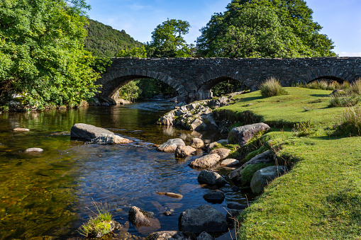 The River Duddon flows under the bridge at the picturesque village of Ulpha on the Sella Brow Road in the Lake District National Park, England.