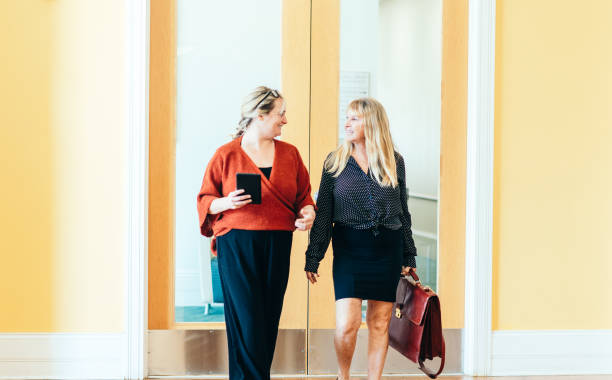 istock Two female professionals walk and have a discussion in a professional modern office 1640098355
